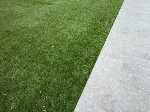Rooftop amenity deck with artificial turf laid beside large-format porcelain pavers, bamboo planters and a pergola